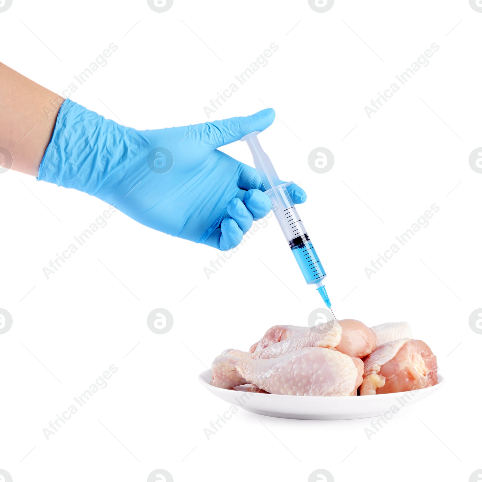 Photo of GMO concept. Scientist injecting something into chicken drumsticks on white background, closeup