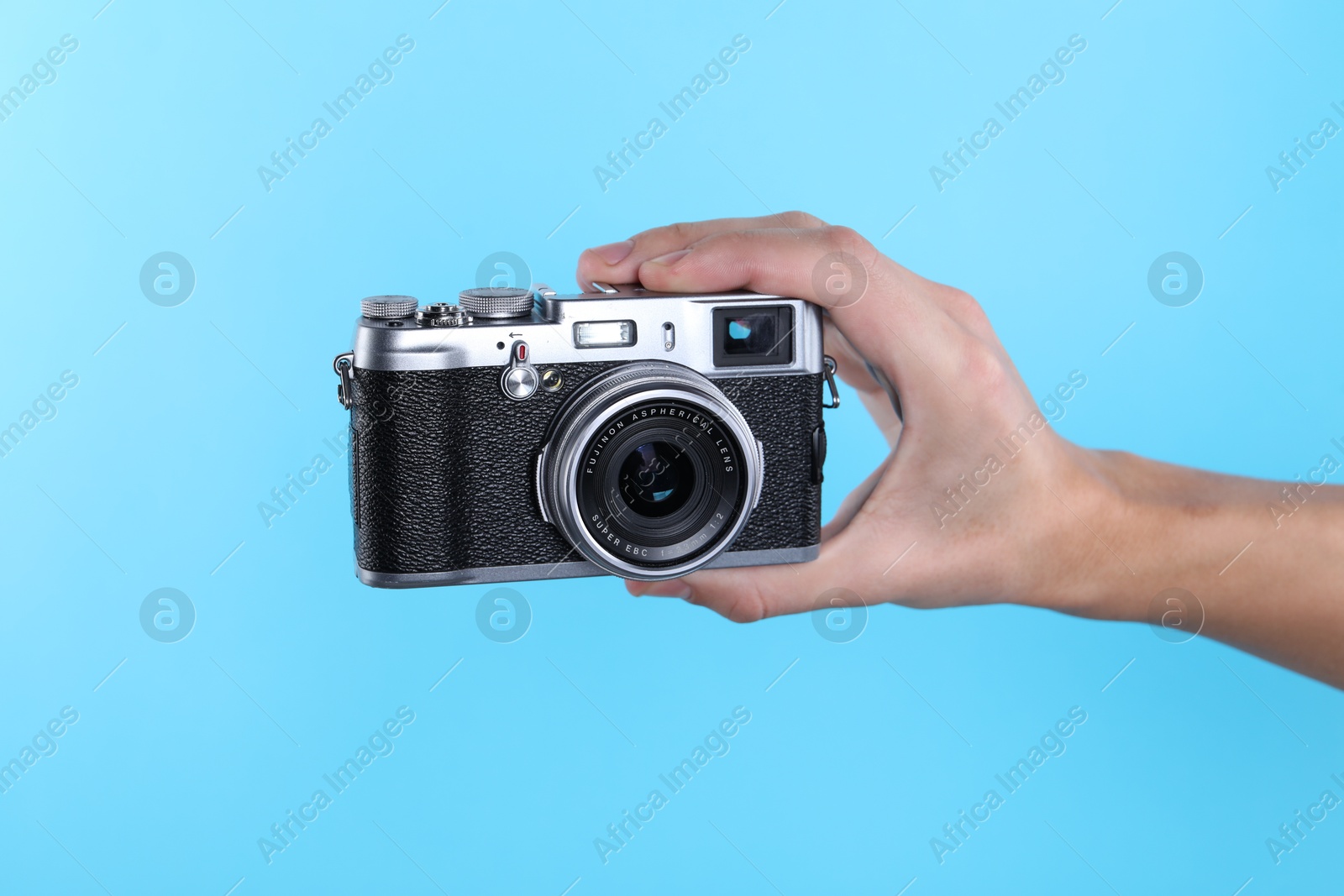 Photo of Photographer with vintage camera on light blue background, closeup