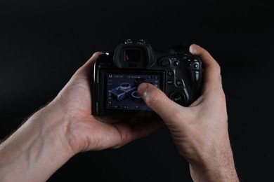 Photo of Photographer taking photo with professional camera on dark background, closeup