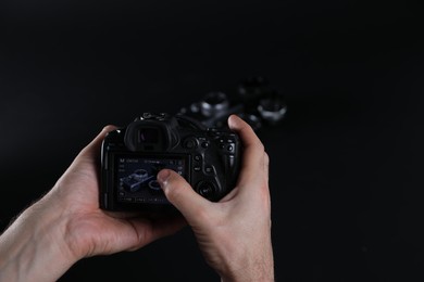 Photo of Photographer taking photo with professional camera on dark background, closeup