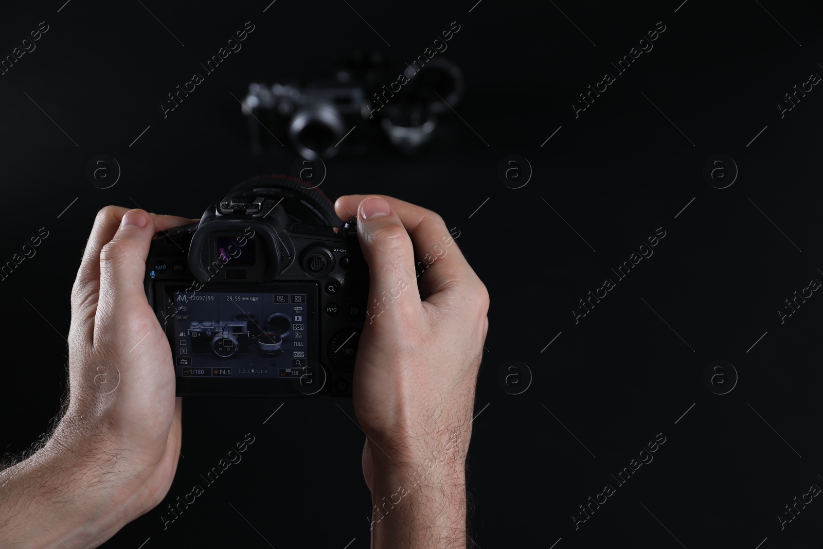 Photo of Photographer taking photo with professional camera on dark background, closeup