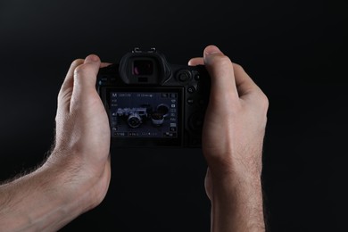 Photo of Photographer taking photo with professional camera on dark background, closeup