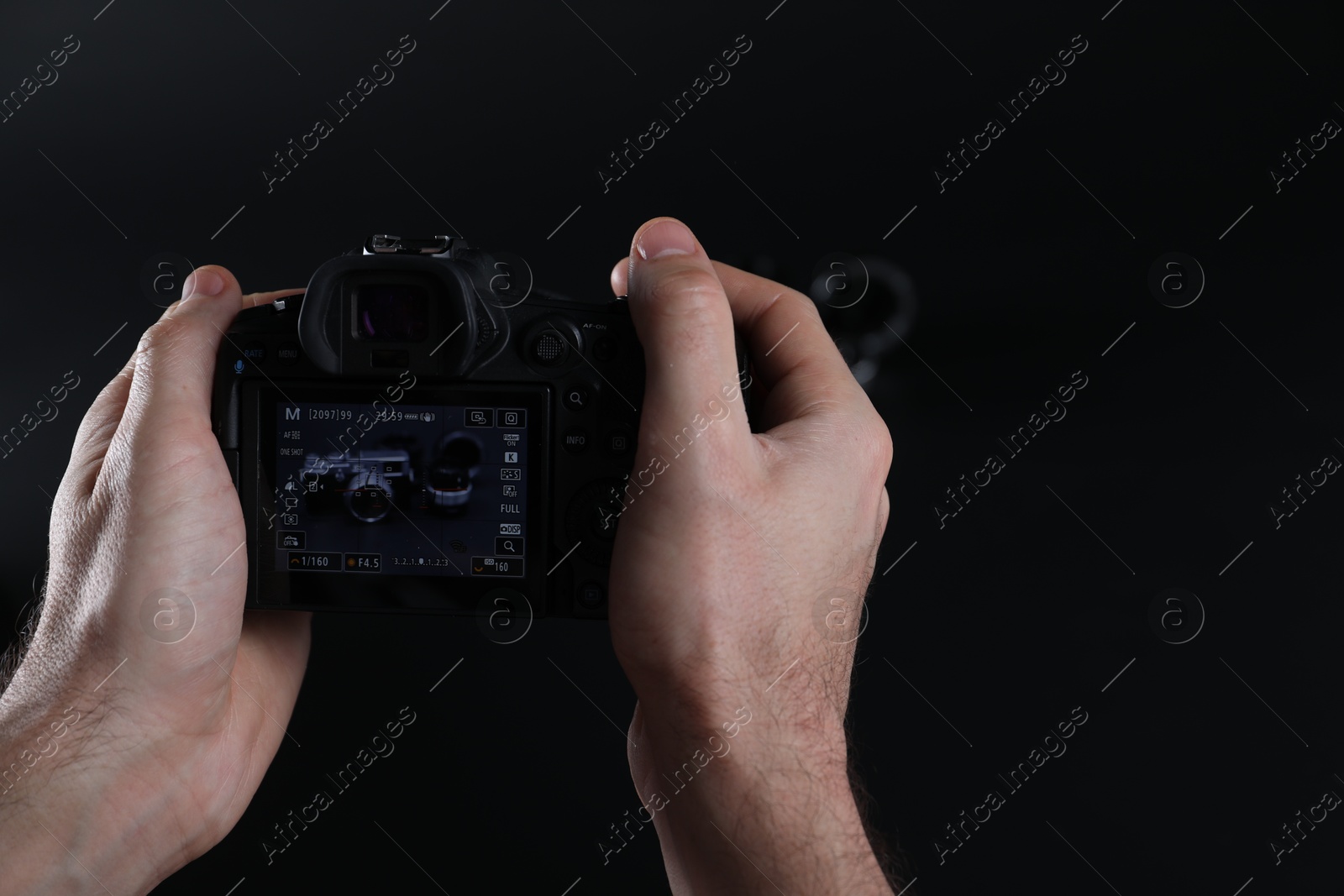 Photo of Photographer taking photo with professional camera on dark background, closeup