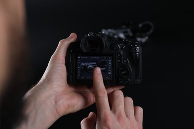 Photo of Photographer taking photo with professional camera on dark background, closeup