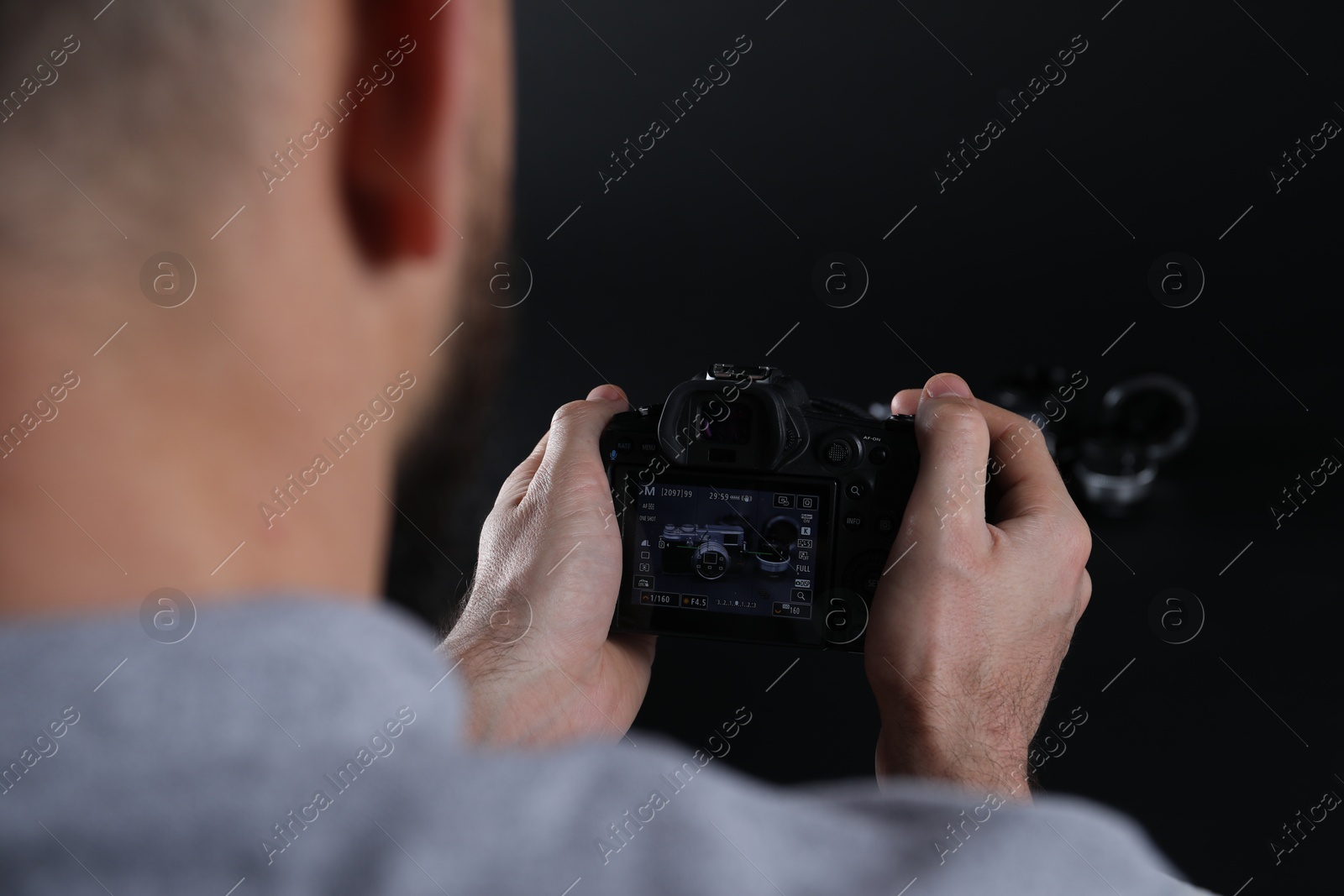 Photo of Photographer taking photo with professional camera on dark background, selective focus