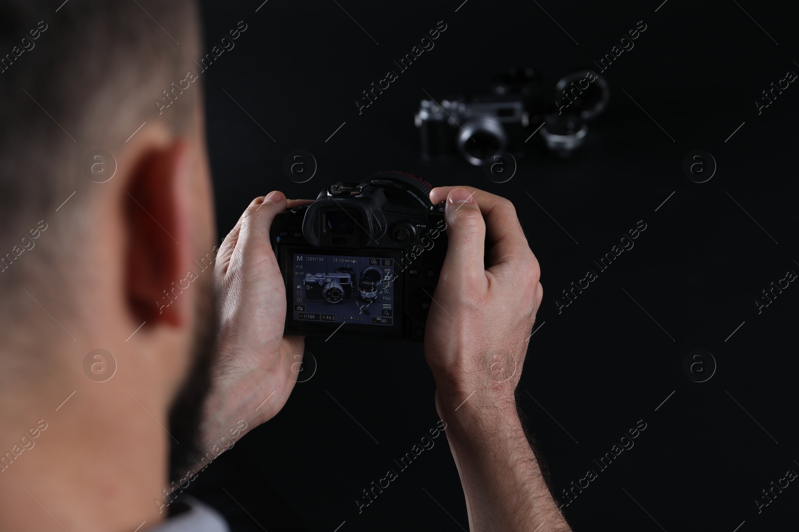 Photo of Photographer taking photo with professional camera on dark background, closeup. Space for text