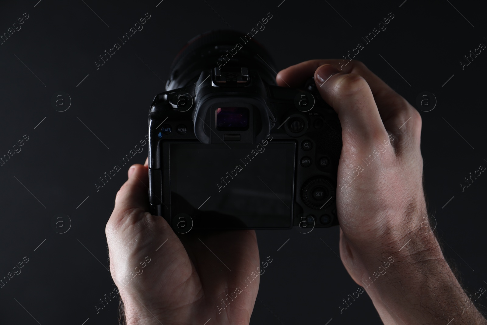 Photo of Photographer with professional camera on dark background, closeup