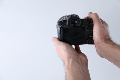 Photo of Photographer with professional camera on white background, closeup. Space for text