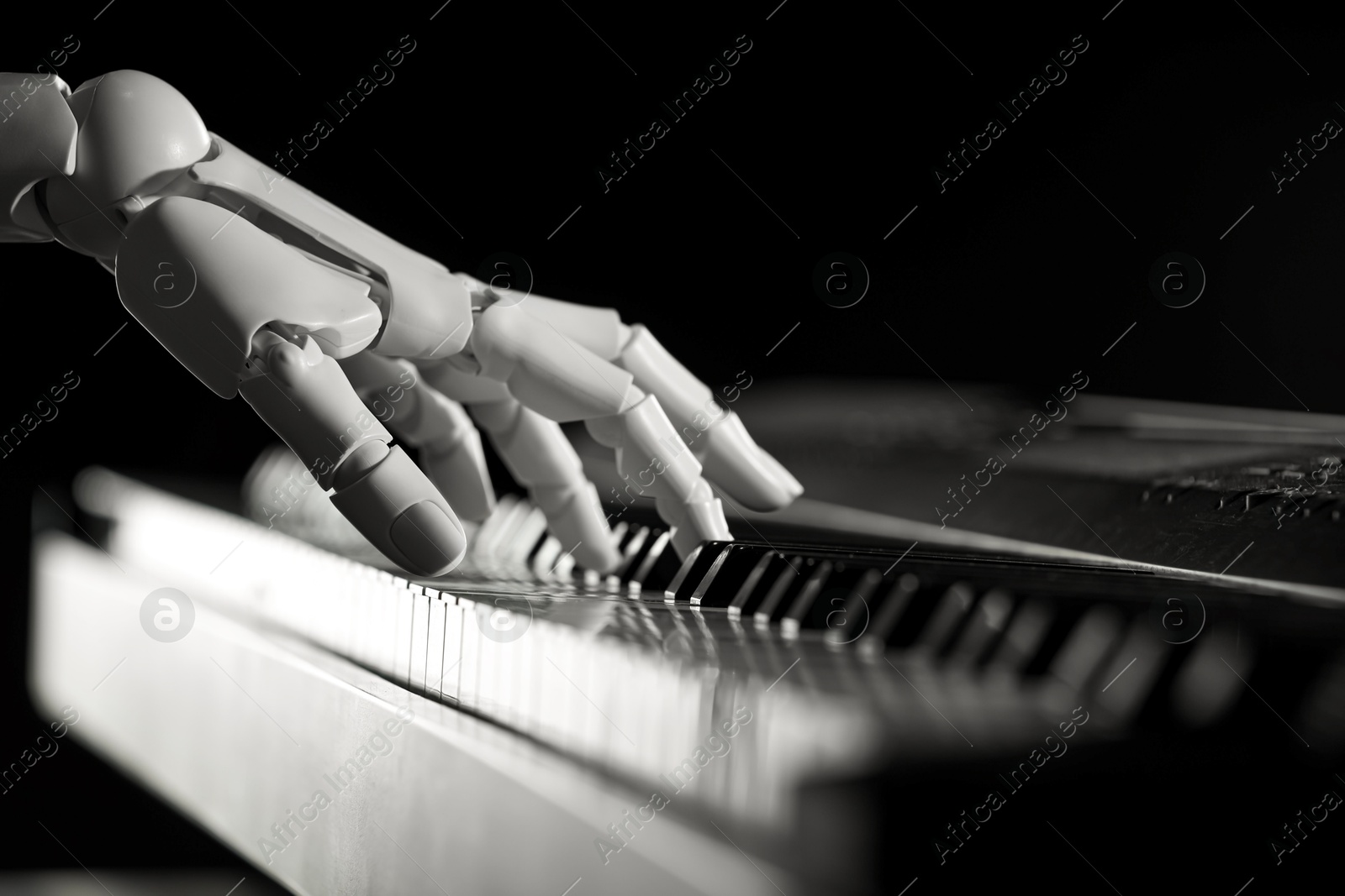 Photo of Artificial intelligence. Robot hand playing synthesizer on black background, closeup