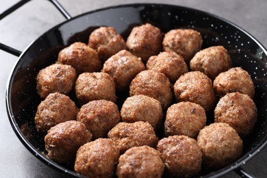 Photo of Tasty meatballs in baking dish on grey table, closeup