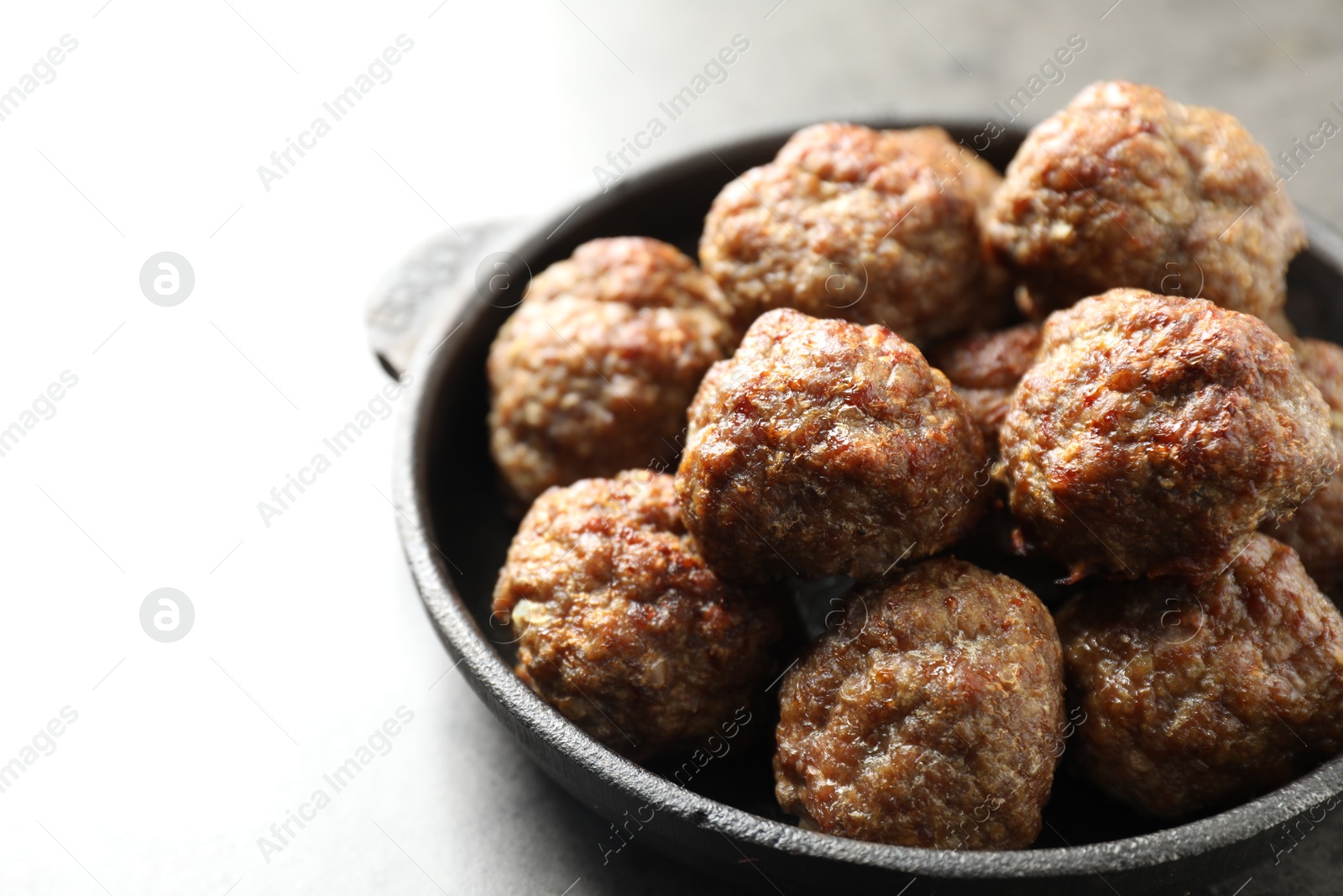 Photo of Tasty meatballs in baking dish on grey table, closeup. Space for text