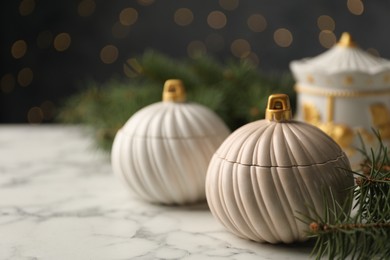 Photo of Soy wax candles and green fir branches on white marble table, closeup with space for text. Beautiful Christmas decor