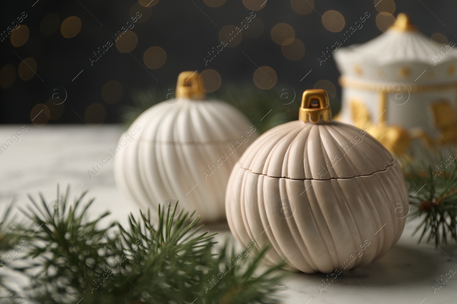 Photo of Soy wax candles and green fir branches on white table, closeup. Beautiful Christmas decor