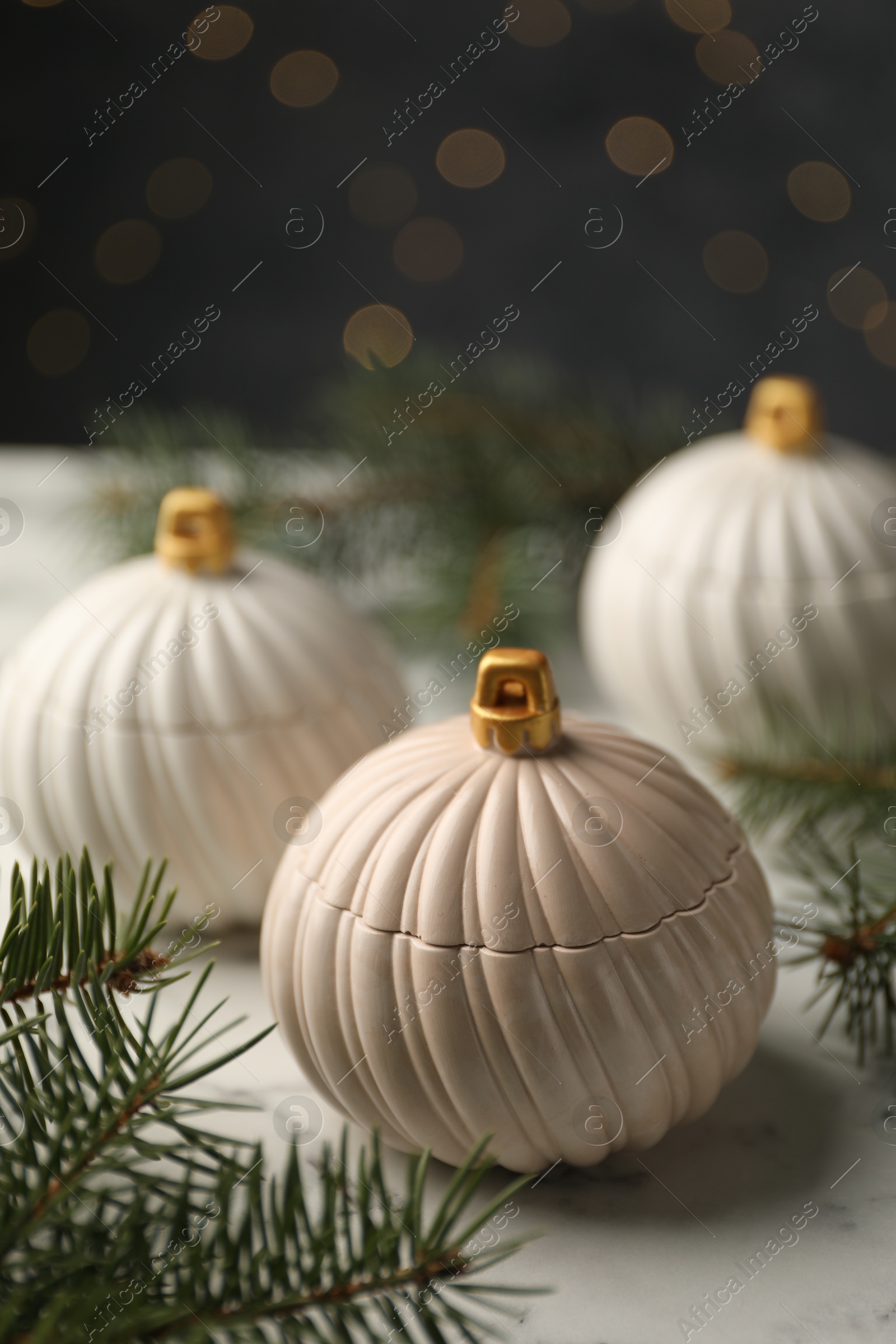 Photo of Soy wax candles and green fir branches on white table, closeup. Beautiful Christmas decor