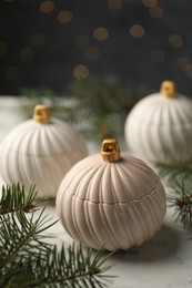 Photo of Soy wax candles and green fir branches on white table, closeup. Beautiful Christmas decor