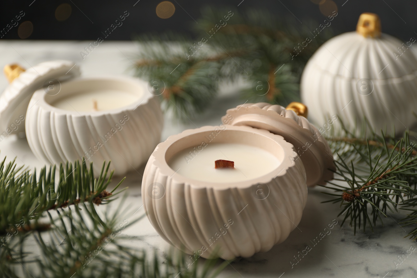 Photo of Soy wax candles and green fir branches on white marble table, closeup. Beautiful Christmas decor