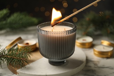 Photo of Lighting soy candle at white marble table, closeup