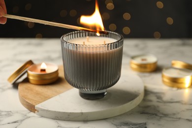 Lighting soy candle at white marble table, closeup