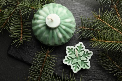 Photo of Soy candles in shape of snowflake and Christmas ball among green fir branches on grey table, flat lay