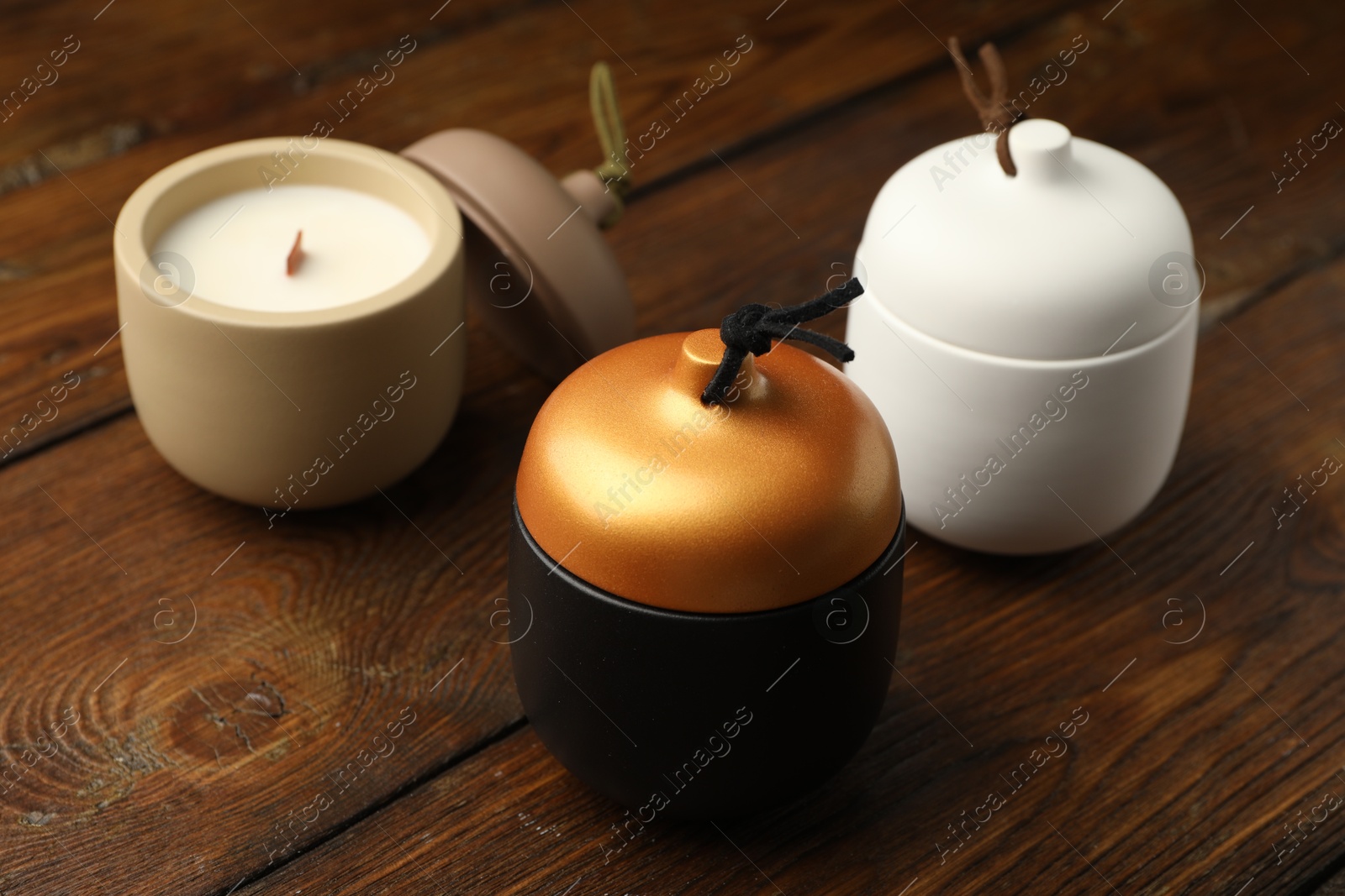 Photo of Different soy candles on wooden table, closeup