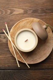 Photo of Soy candle and matches on wooden table, top view