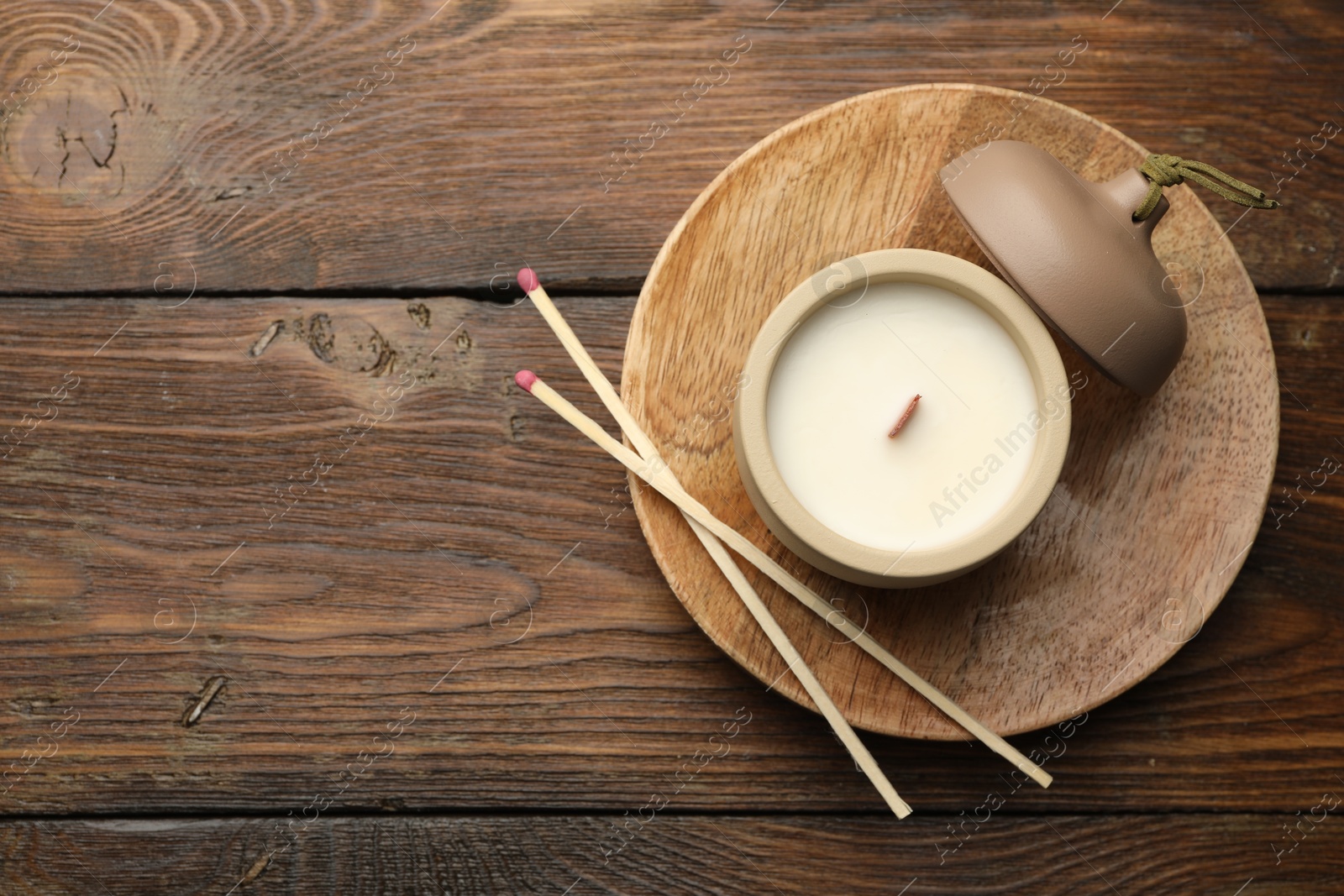 Photo of Soy candle and matches on wooden table, top view. Space for text