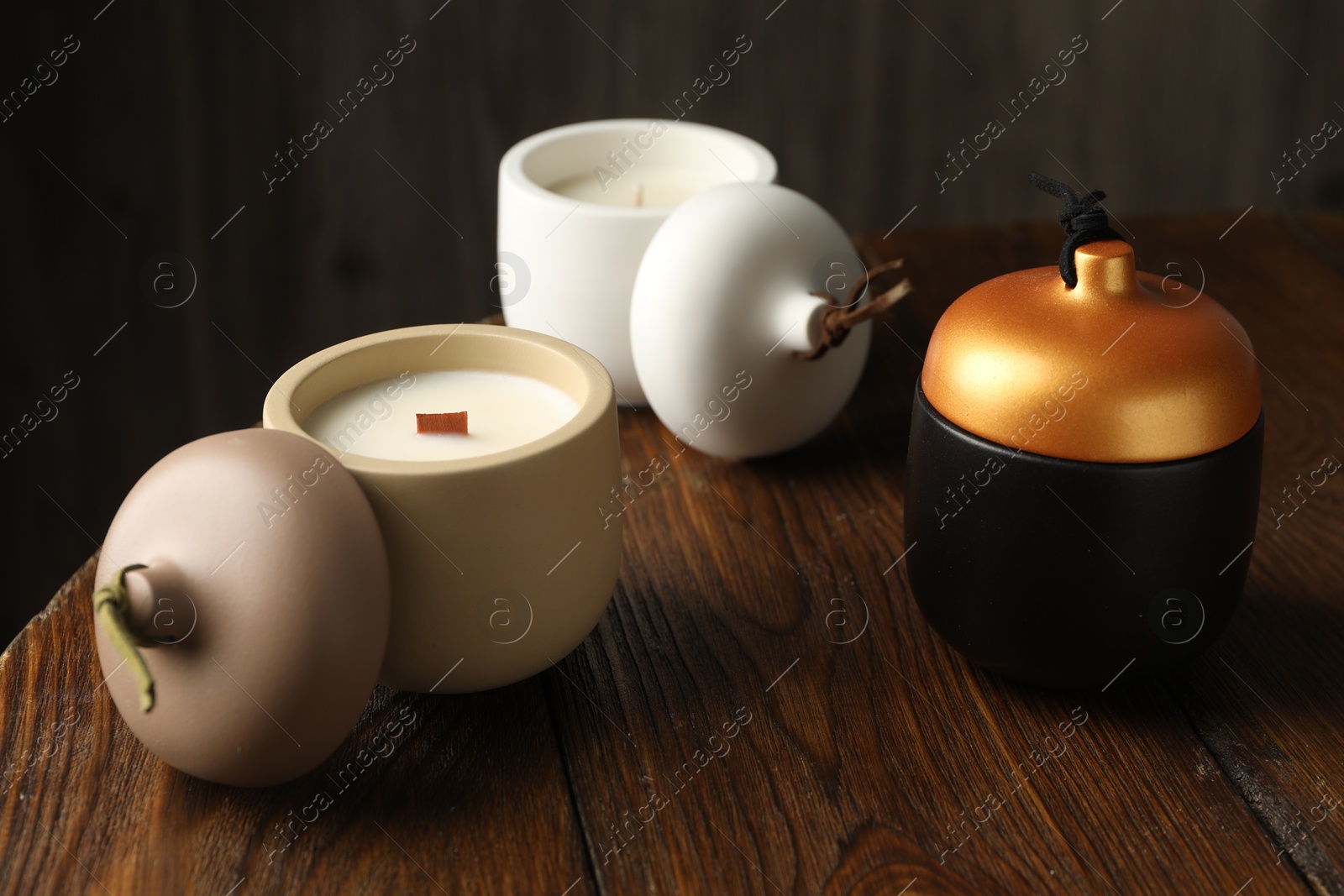 Photo of Different soy candles on wooden table, closeup