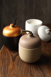 Photo of Different soy candles on wooden table, closeup