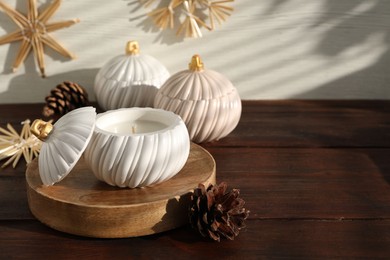 Photo of Soy wax candles and cones on wooden table, space for text. Beautiful christmas decor