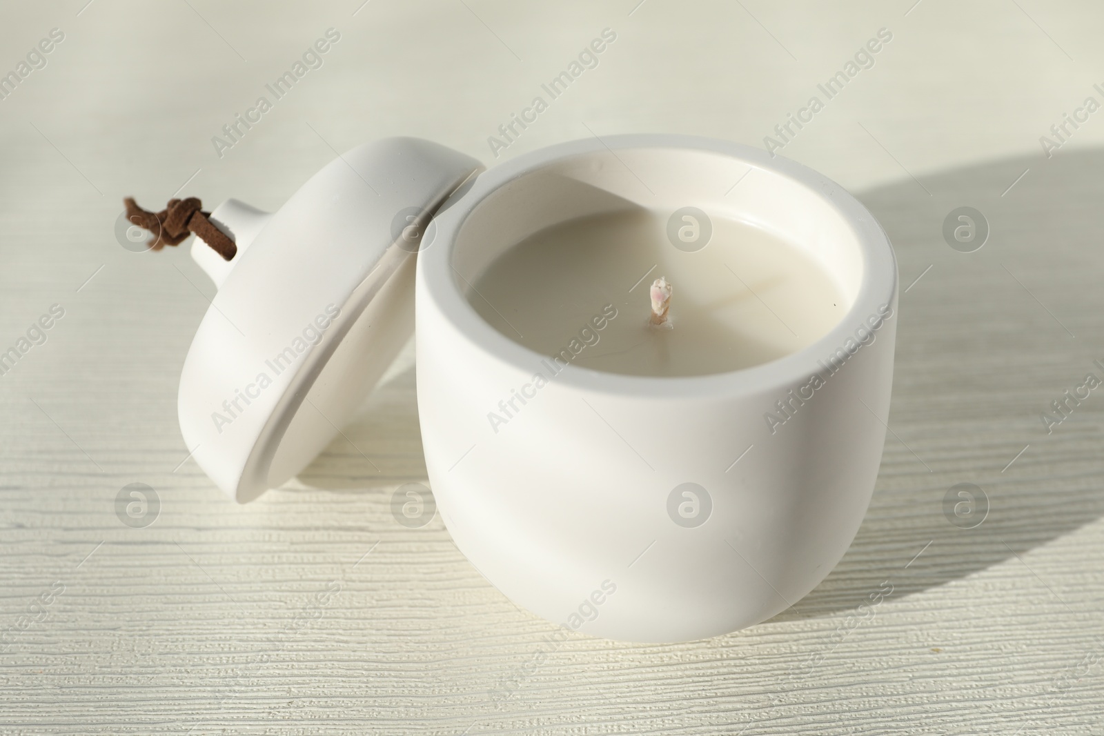 Photo of Soy candle and lid on white wooden table, closeup