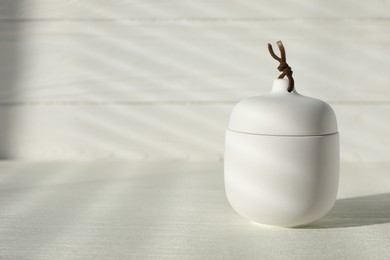 Soy candle and lid on white wooden table, space for text