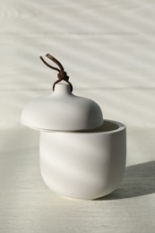 Soy candle and lid on white wooden table, closeup