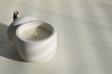 Photo of Soy candle and lid on white wooden table, space for text