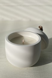 Photo of Soy candle and lid on white wooden table, closeup