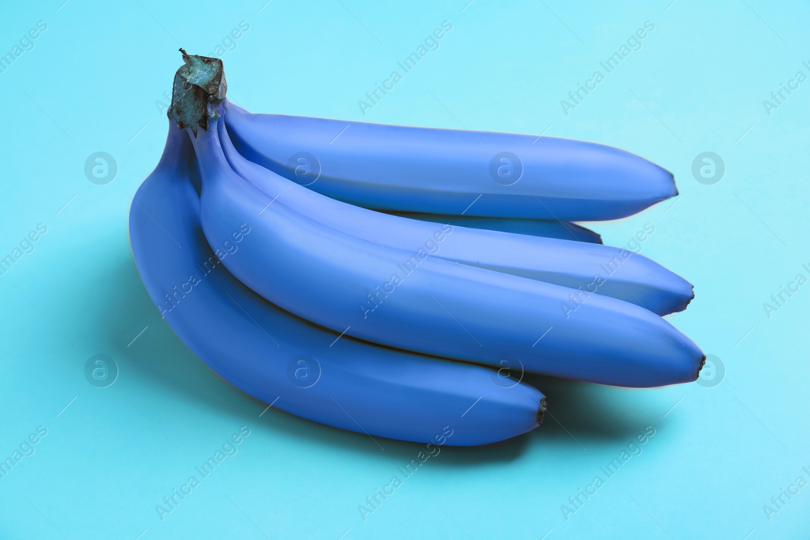 Image of Bunch of blue violet bananas on turquoise background