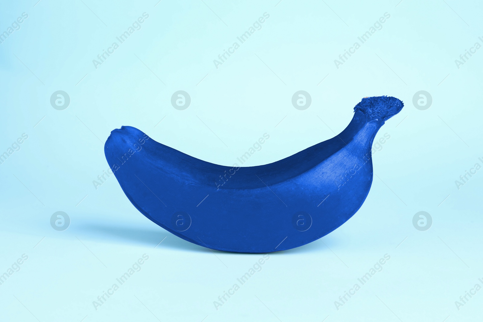 Image of One blue banana on light blue background