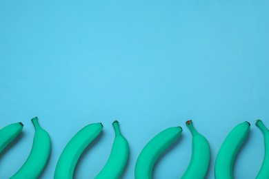 Image of Turquoise bananas on light blue background, flat lay. Space for text