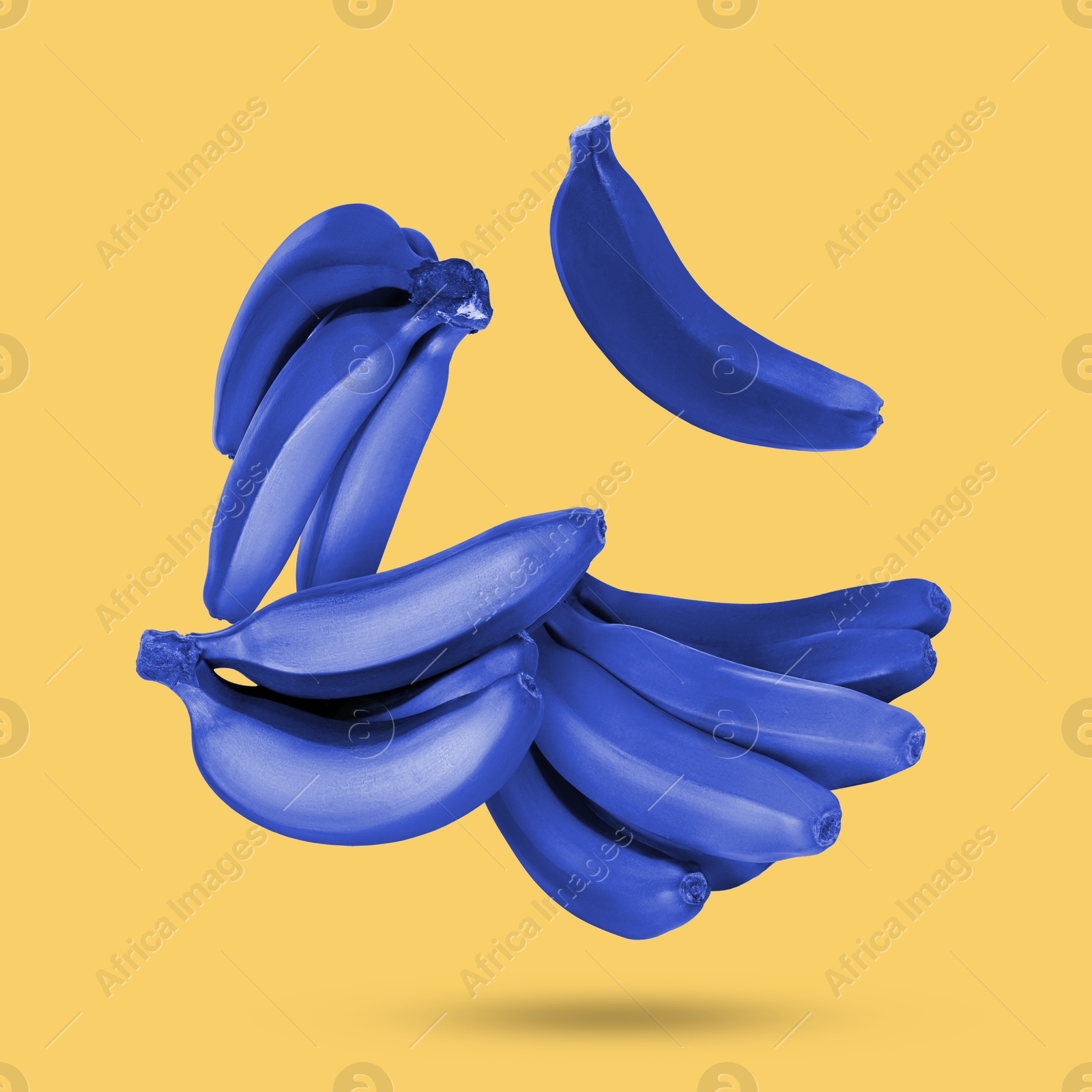 Image of Blue bananas in air on light orange background