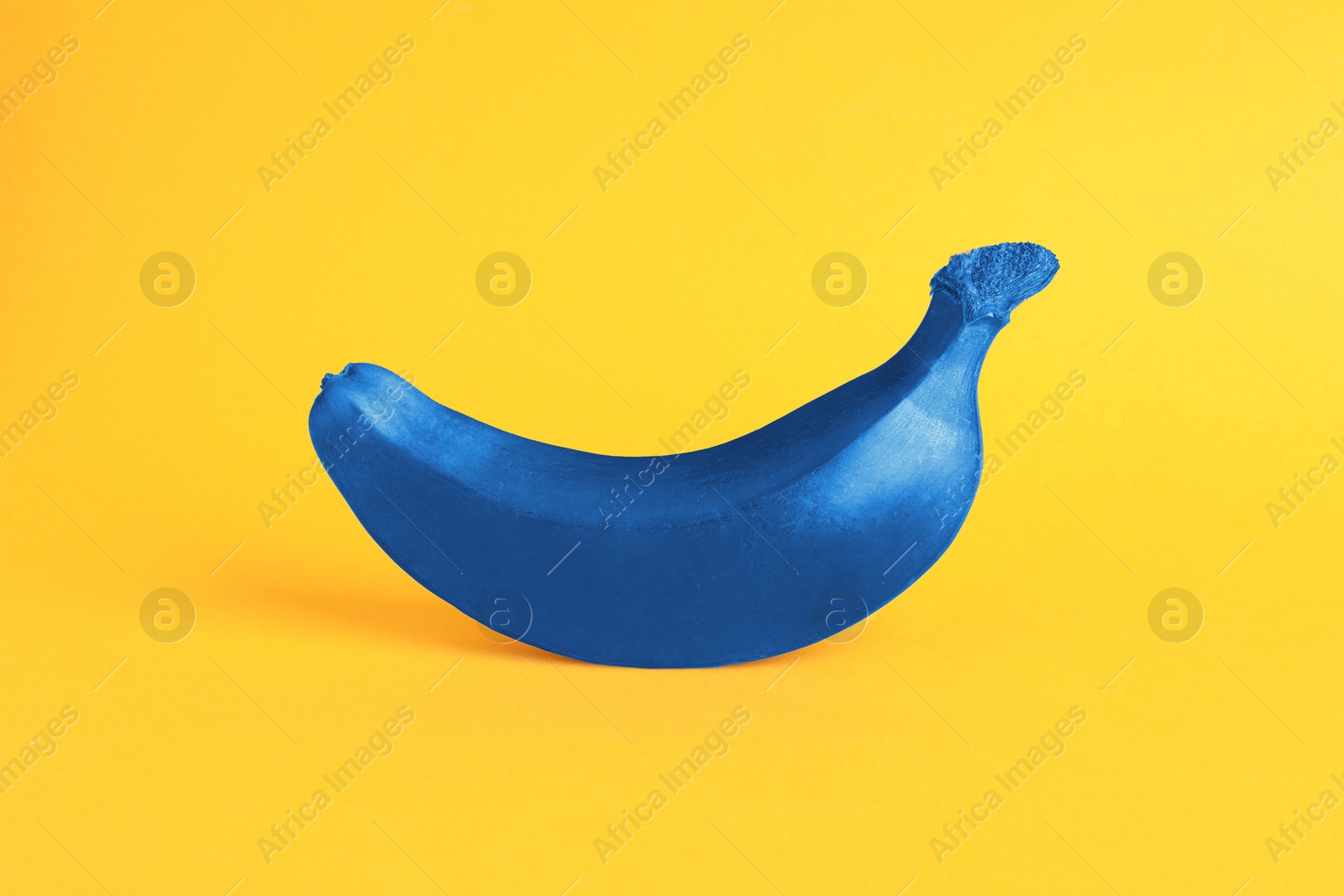 Image of One blue banana on yellow background. Tropical fruit