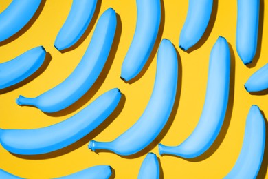 Image of Light blue bananas on yellow background, flat lay