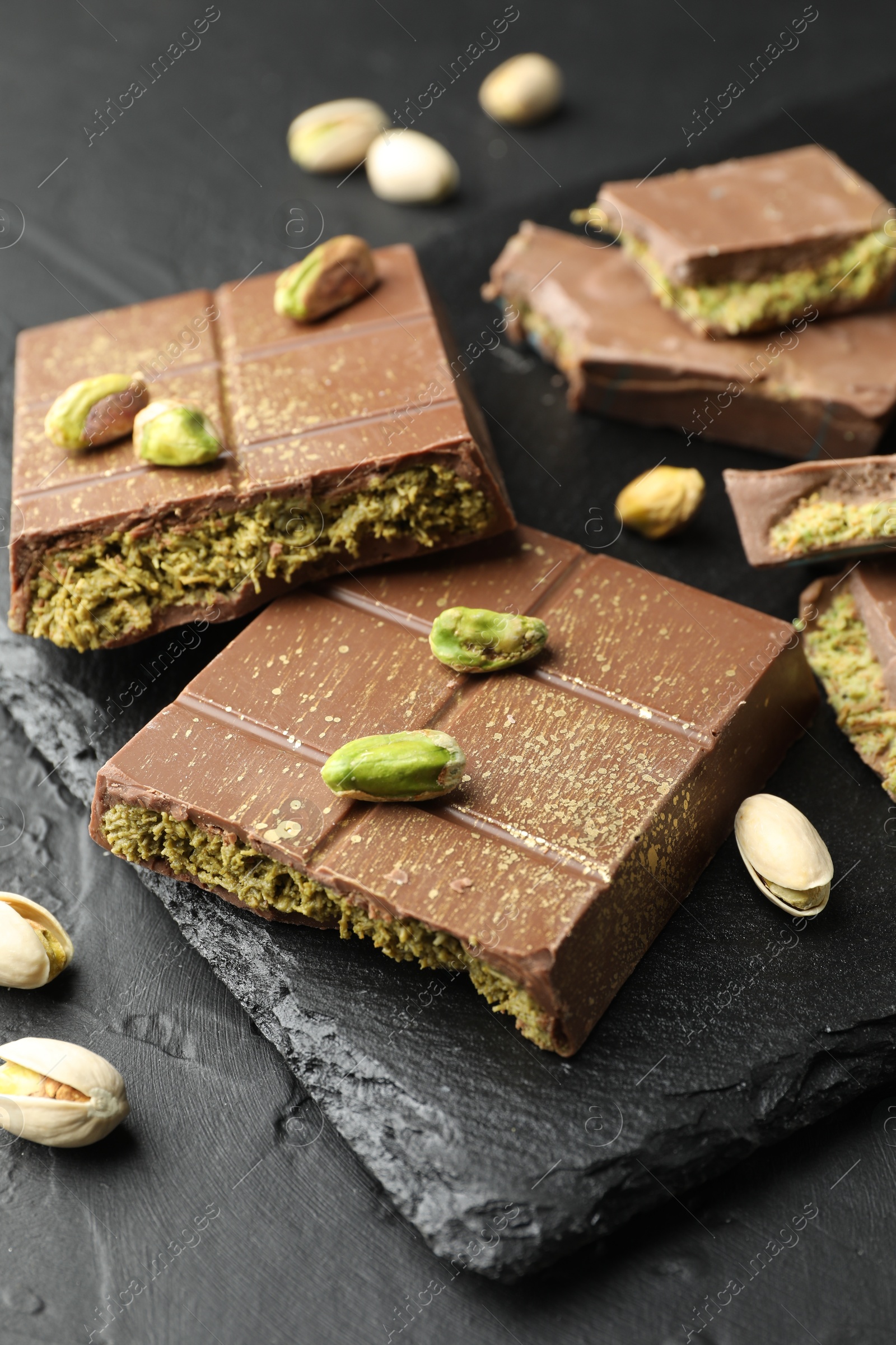 Photo of Pieces of Dubai chocolate bars with pistachios and knafeh on grey table, closeup