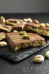 Photo of Pieces of Dubai chocolate bars with pistachios and knafeh on grey table, closeup