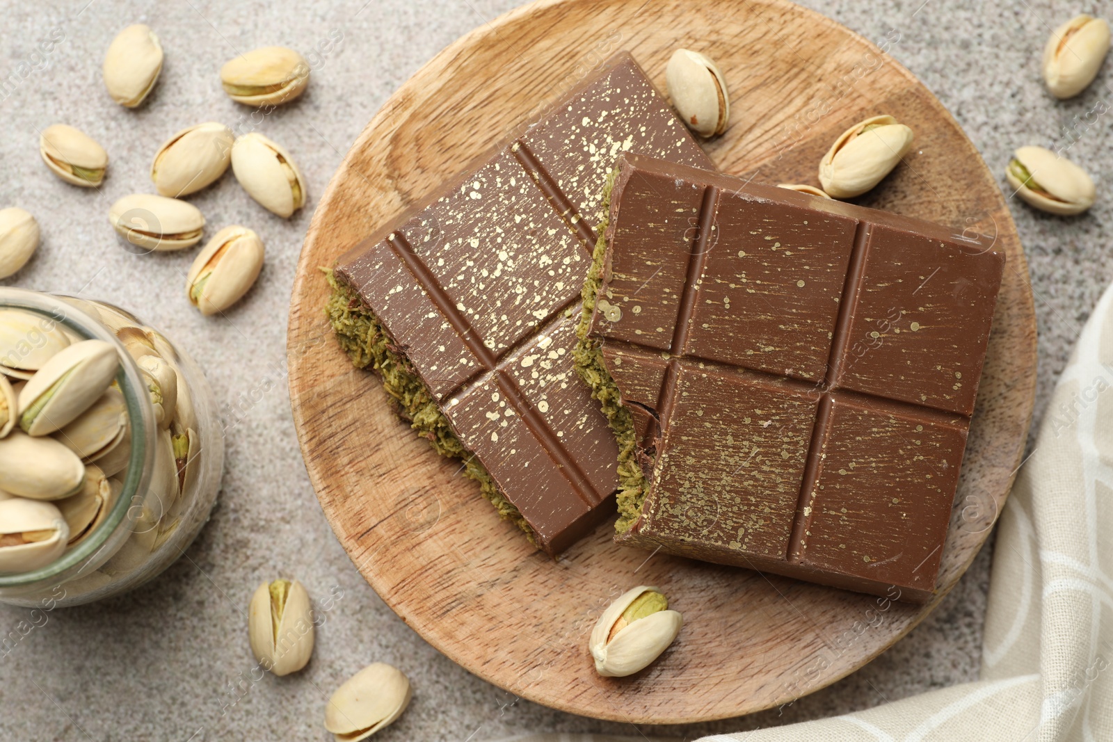 Photo of Pieces of Dubai chocolate bar with pistachios and knafeh on grey table, flat lay