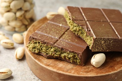 Photo of Pieces of Dubai chocolate bar with pistachios and knafeh on grey table, closeup