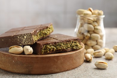 Photo of Pieces of Dubai chocolate bar with pistachios and knafeh on grey table, closeup