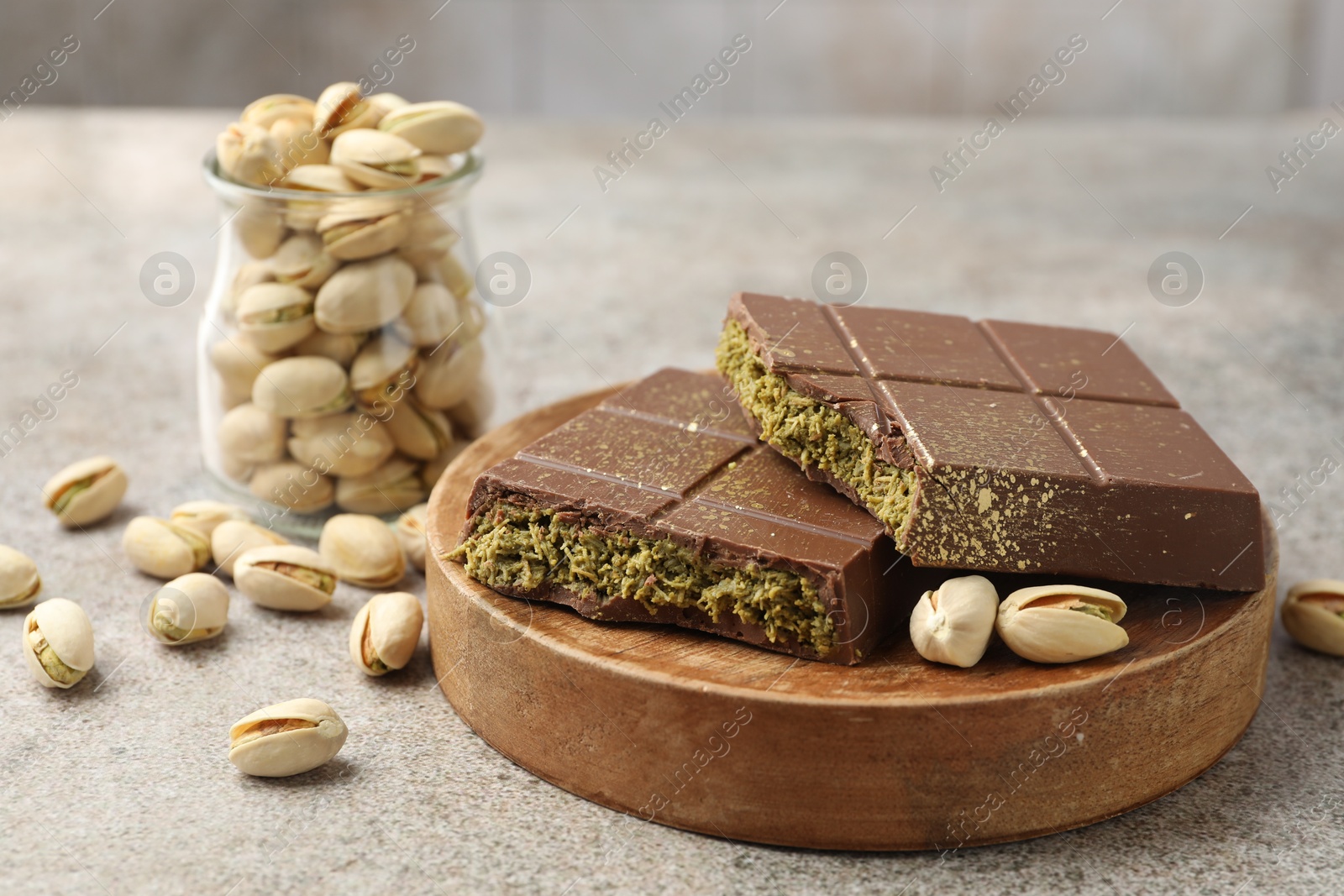 Photo of Pieces of Dubai chocolate bar with pistachios and knafeh on grey table, closeup