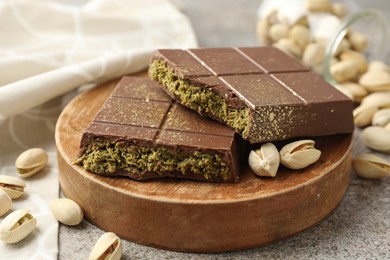 Photo of Pieces of Dubai chocolate bar with pistachios and knafeh on grey table, closeup