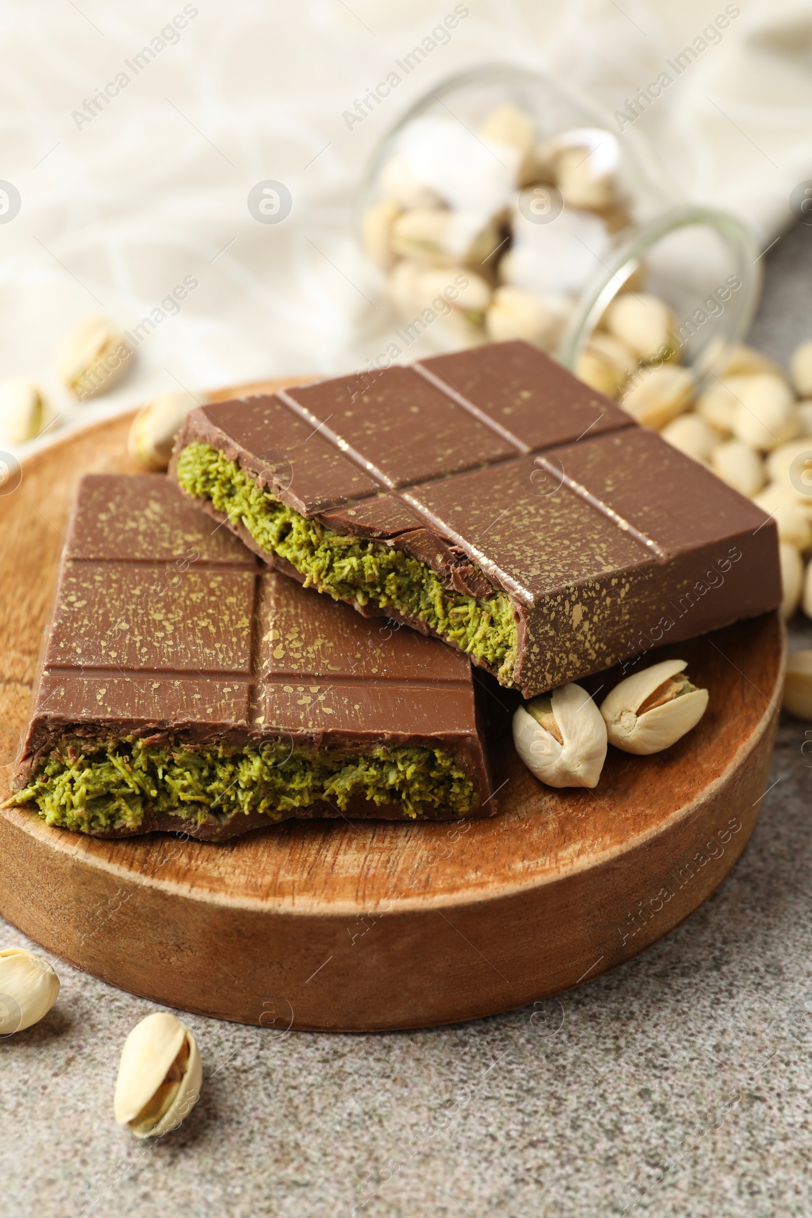 Photo of Pieces of Dubai chocolate bar with pistachios and knafeh on grey table, closeup