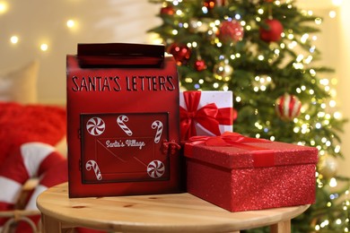 Photo of Santa Claus mailbox and gift boxes on wooden table indoors. Christmas atmosphere