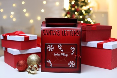 Photo of Santa Claus mailbox, gift boxes and Christmas decor on white table indoors